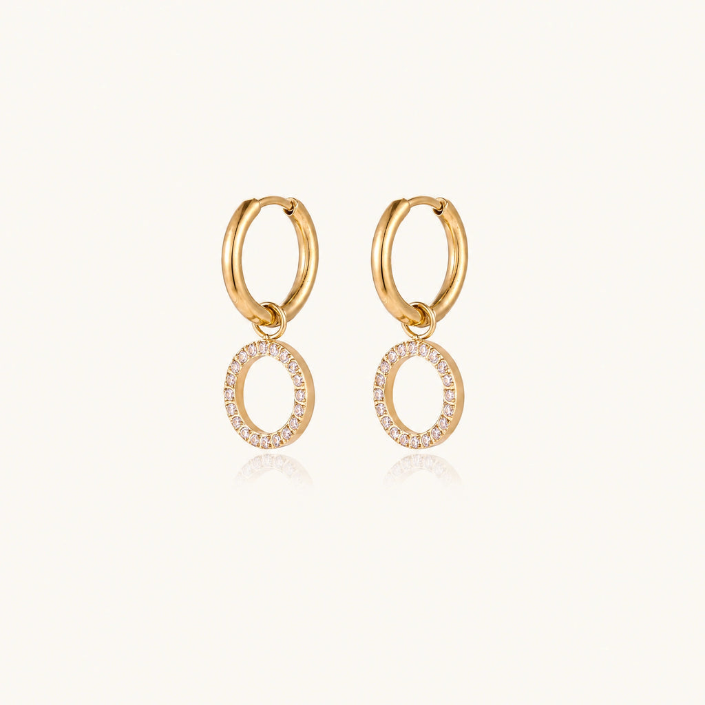 Gold-plated huggie hoop earrings with CZ-studded open circle charms on beige background