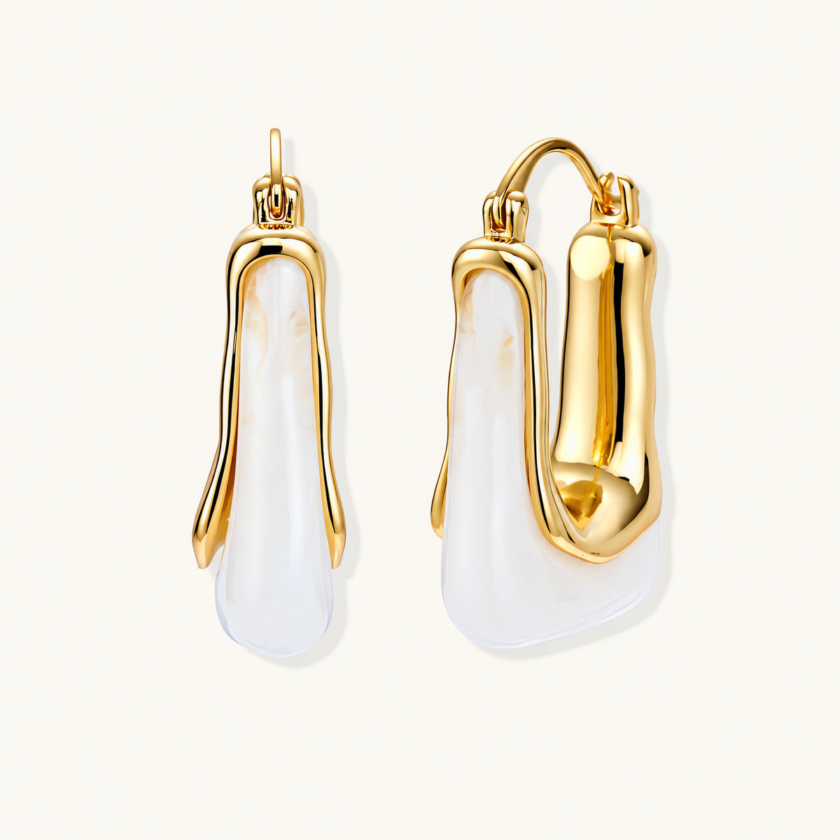 Sculptural gold-plated hoop earrings with flowing curved design and lever-back closure on cream background.