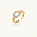 Gold-plated brass chain link ring with one oval CZ-pavé segment on cream background, adjustable cuff style.