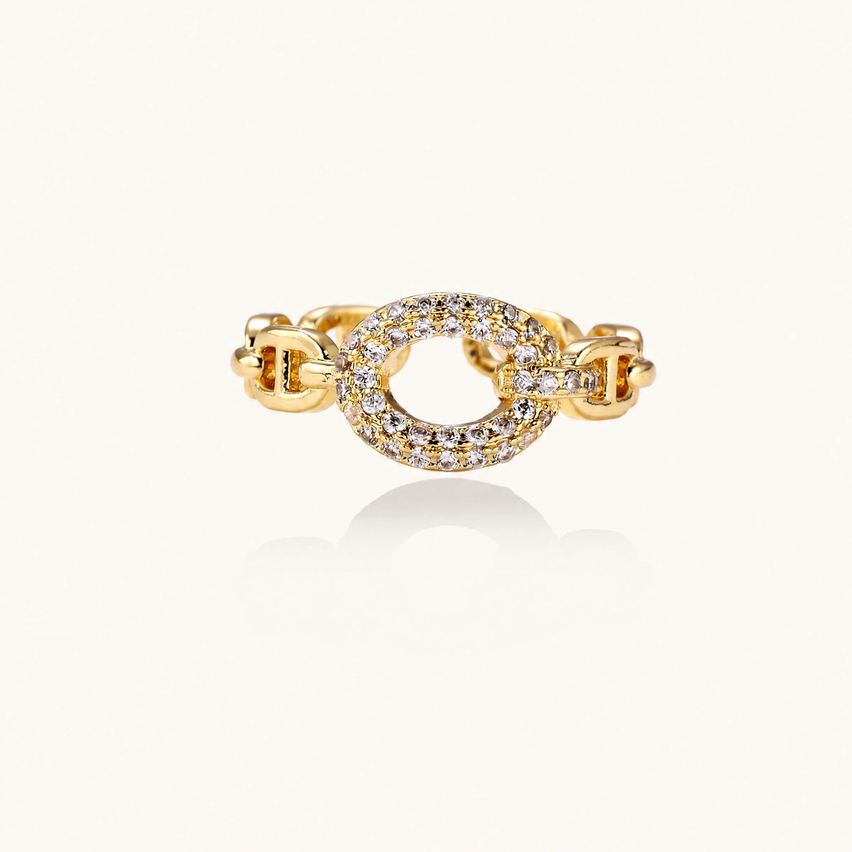 Gold-plated brass chain link ring with one oval CZ-pavé segment on cream background, adjustable cuff style.