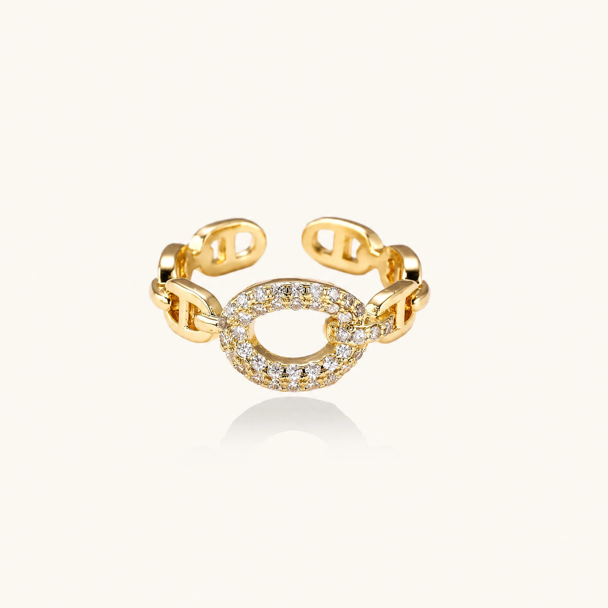 Gold-plated brass chain link ring with one oval CZ-pavé segment on cream background, adjustable cuff style.
